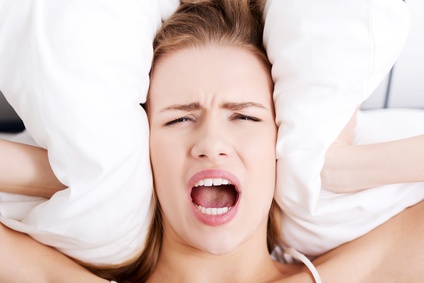 Beautiful business woman lying in bed and covering her ears with